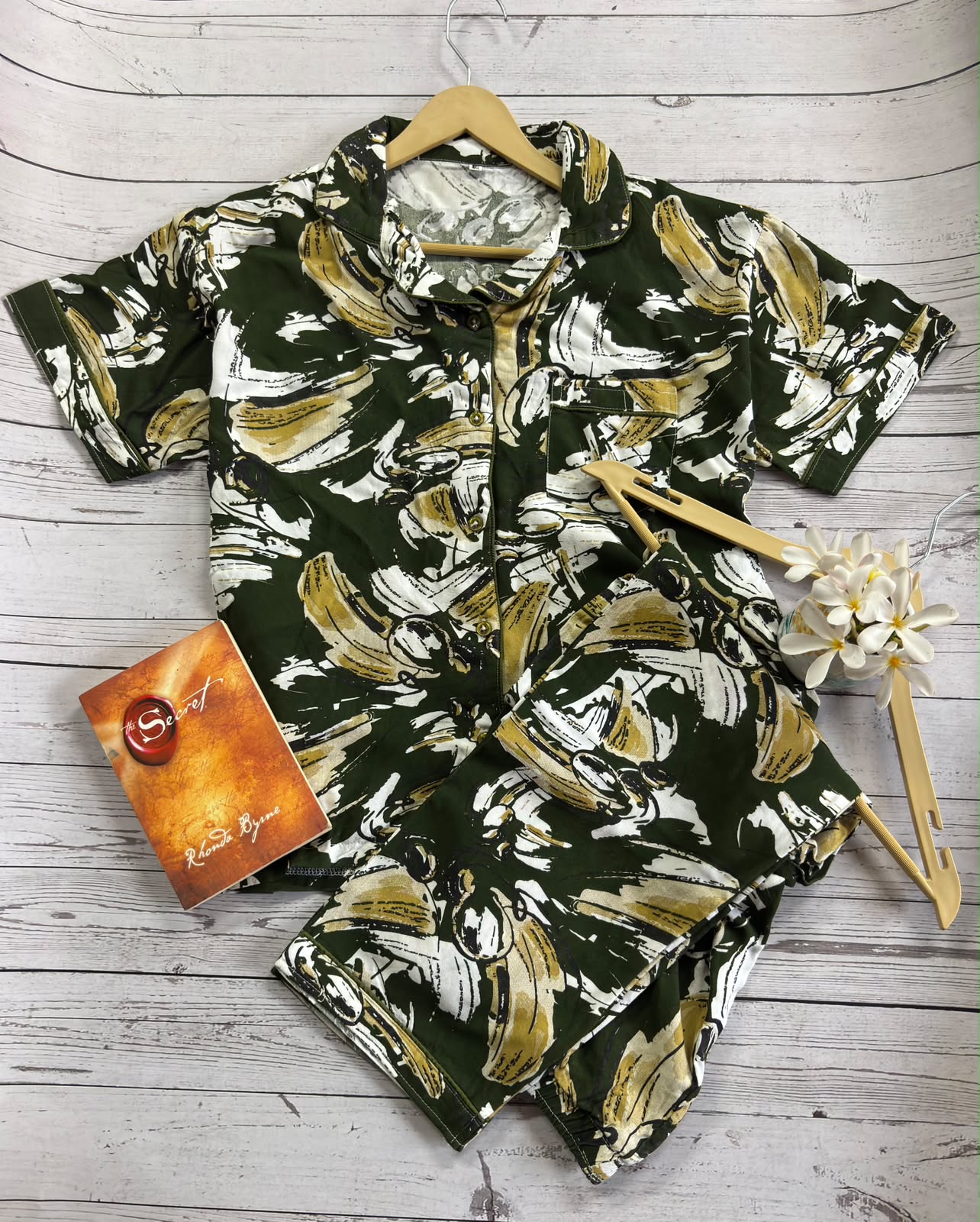Floral patterned shirt on a wooden surface with a card and flower decoration.